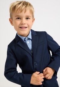 Marineblå dressjakke med en enkelt knapp, kombinert med en lyseblå skjorte med en subtil tekstur, som viser skreddersydd passform og rene linjer.