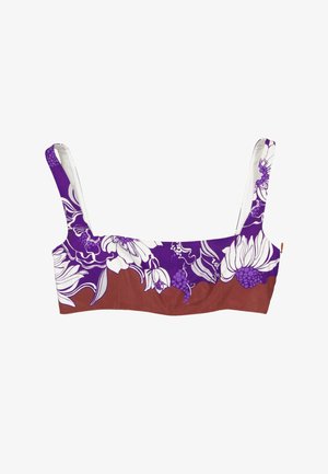 Top de sujetador con tirantes anchos con un estampado floral púrpura y blanco sobre un fondo marrón.