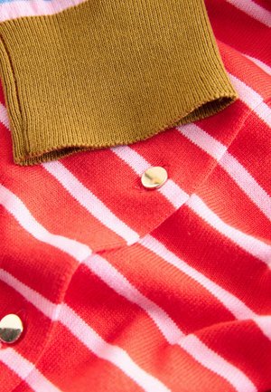 Röd och vit randig tyg med en brun ribbad krage. Har en metallisk guldkknapp. Mjuk textur, närbild.