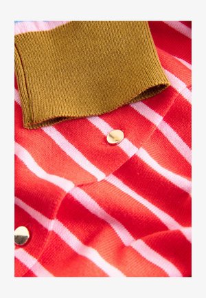 Červeno-bíle pruhovaná látka s hnědým žebrovaným límcem. Obsahuje kovový zlatý knoflík. Měkká textura, pohled zblízka.