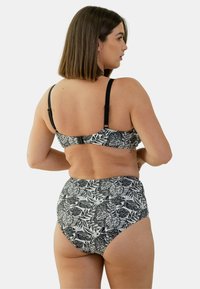 Ensemble de bikini noir et blanc présentant un motif de feuilles florales ; le haut possède des bretelles ajustables, et le bas taille haute offre une couverture totale.