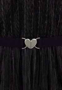 Violetās krokotas auduma ar metāliskām šķiedrām, ar melnu elastīgu jostu un sudraba sirds formas aizdari centrā.