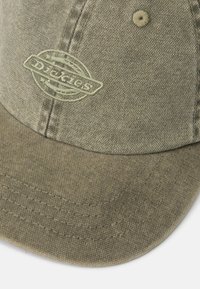Căciulă din țesătură verde măsliniu cu un patch rotund cu logo-ul Dickies, design în șase panouri, cusături vizibile și o vizieră ușor curbă.