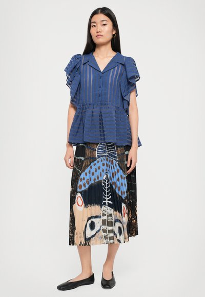 Blue striped blouse with ruffled sleeves, paired with a black pleated skirt featuring colorful abstract patterns. Black flats complete the look.