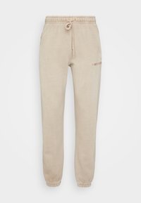 Beige fleecebyxor med resårmidja, justerbar dragsko och avsmalnande ben. Har diskret logotyp på sidan.