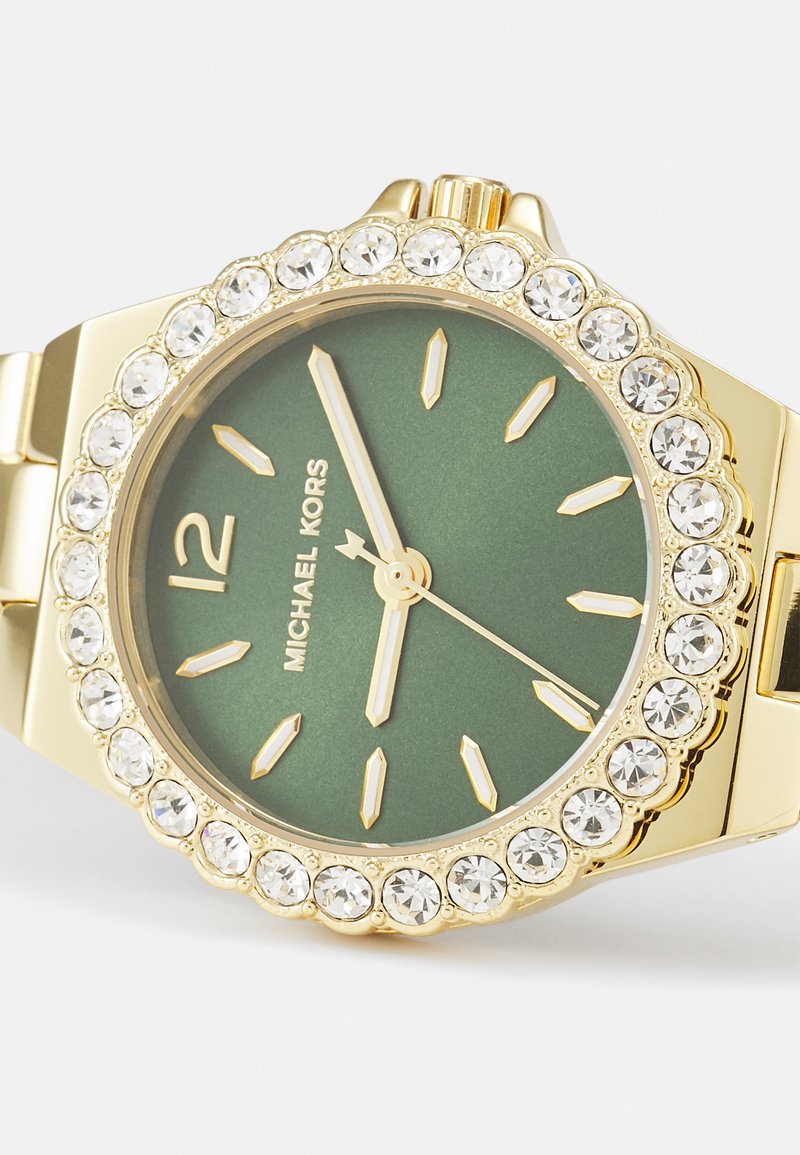 Goldfarbene Uhr mit grünem Ziffernblatt, mit Kristallen akzentuiertem Gehäuserand und goldenen Stundenmarkierungen. Verfügt über einen klassischen Armband-Stil und ein auffälliges Logo bei 12 Uhr.