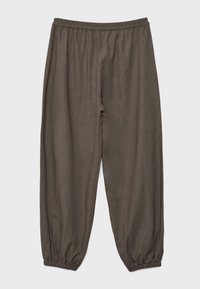 Pantalon marron ample avec taille élastique et bas de jambe élastiques aux chevilles sur un fond uni.