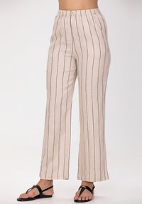 Pantalons en lin beige clair avec des rayures verticales noires, taille élastique et jambes larges. Présente une légère texture pour un confort optimal.