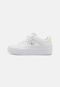 White low-top sneaker with thick sole, mesh and leather panels, Calvin Klein Jeans logo in gold, and neon yellow heel tab.