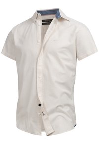 Camisa de manga corta de color crema hecha de algodón, con un acento en el cuello de color azul marino y un sutil bordado de logo en el pecho.
