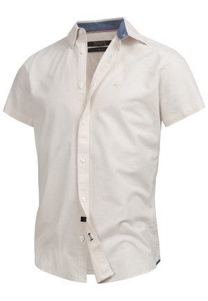 Krátký rukáv, krémová košile vyrobená z bavlny, s tmavě modrým límcem a jemnou výšivkou loga na hrudi.