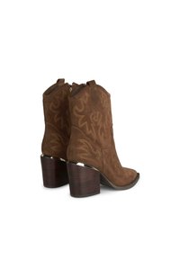 Botas vaqueras de ante marrón con patrones bordados, puntera ligeramente afilada y un tacón de madera grueso. Presenta un cierre con cremallera en el costado.