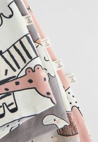 Conjunto de cuatro camisetas de algodón para niños en diferentes colores: crema, rosa, gris y con estampados de ilustraciones de animales. Las etiquetas dicen "SALVAJE Y LIBRE".
