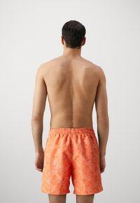 Boxeri de înot pentru bărbați, portocalii, cu un model alb de frunze, talie elastică și un singur buzunar pe spate. Material neted, ușor.