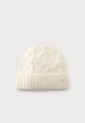 Bonnet tricoté de couleur crème avec motif torsadé et bord replié en côtes, présenté sur un fond clair uni.