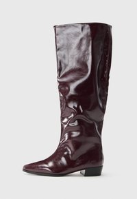 Knee-high burgundy boots made of glossy synthetic material, featuring a pointed toe and a low block heel with a smooth texture.
