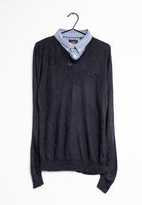 Granatowy sweter z długim rękawem i dekoltem w serek, założony na jasnoniebieską koszulę w białą kratę z kołnierzykiem. Gładka tekstura i swobodny design.
