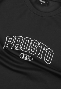 Czarna koszulka z białym napisem "PROSTO XXX" na klatce piersiowej, z widoczną metką oznaczającą rozmiar "L."