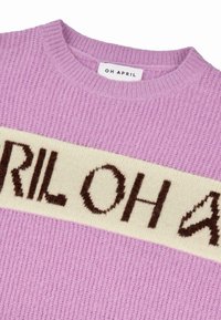 Pull en maille lilas avec une rayure horizontale crème portant le texte "OH APRIL" en marron. Texture côtelée, encolure ronde.