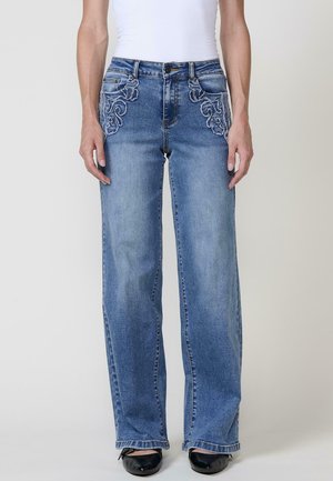 Jeans de mezclilla de color azul claro con bordados intrincados en los bolsillos delanteros. Corte de pierna ancha con un dobladillo limpio y cierre de botón clásico.