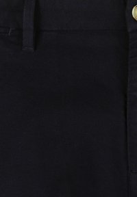 Dunkel marineblauer Stoff mit glatter Textur, versehen mit einer vertikalen Naht und einem goldenen Knopfdetail an der Taille, das auf einen Bund hinweist.