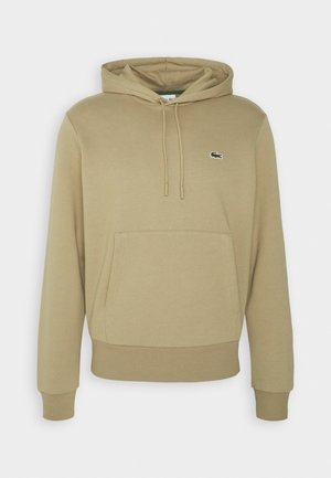 Sweat à capuche beige avec poche kangourou sur le devant, capuche avec cordon, poignets et bas côtelés, avec un petit logo crocodile vert sur la poitrine.