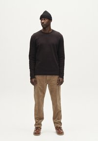 Donkerbruine longsleeve shirt, tan corduroy broek en bruine leren schoenen, met een zwarte gebreide beanie. Eenvoudig, getailleerd ontwerp en gestructureerde stoffen.