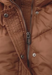 Giacca marrone trapuntata con zip e bottoni metallici, caratterizzata da una texture liscia e un design casual, evidenziando dettagli funzionali.