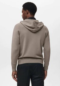 Capuchon sweatshirt in neutraal beige, met ribgebreide mouwen en onderrand, zachte textuur en minimalistisch ontwerp. Gezien vanuit de achterkant.
