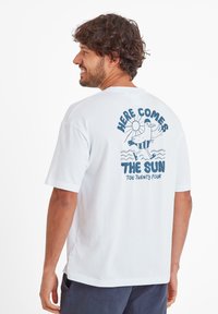 White cotton t-shirt with short sleeves, featuring a blue graphic on the back that includes text and a cartoon bird above wavy lines.