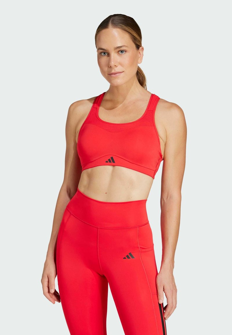 Rode sportbeha en high-waisted legging, beide met een slank ontwerp met een zwart logo-accent en een gladde, rekbare stof.