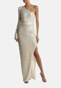 Cremevärvi, ühte õlga kattev sädelev kleit, keha külge liibuv disain, kõrge lõhik reie kõrgusel, tekstureeritud kangas ja üks pikk varrukas.