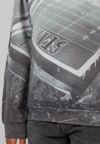 Grijze sweatshirt met een gedrukt ontwerp van een sportstadion met een menigte, met details van het veld en de omringende gebieden.