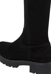 Black suede knee-high boot with a thick rubber sole, featuring visible stitching along the side and a smooth texture.