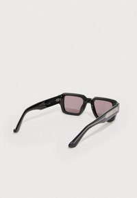 Czarne okulary przeciwsłoneczne z kanciastymi oprawkami, różowymi soczewkami i teksturowanymi srebrnymi akcentami na zausznikach. Gładkie wykończenie z eleganckimi, zakrzywionymi ramionami.