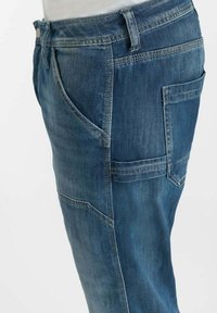 Donkerblauwe denim jeans met een slim-fit ontwerp, voor- en achterzakken, en zichtbare stiksels aan de zijkanten.