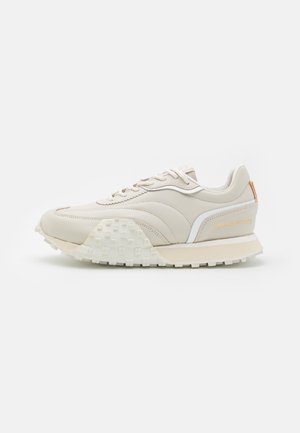 Sneaker beige basso con suola testurizzata, dettagli bianchi, lacci e marchio "Filling Pieces" sul lato e sulla linguetta del tallone posteriore.