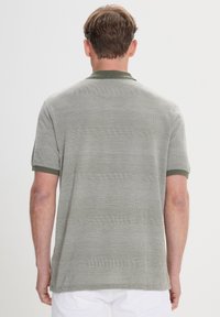 Polo de manga corta en verde oliva con rayas texturizadas y cuello en un verde oscuro contrastante. Corte clásico con un acabado suave.