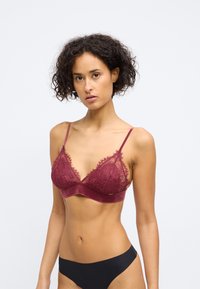 Bralette de encaje burdeos con copas suaves y tirantes ajustables, que presenta una banda lisa y un delicado detalle de flecos a lo largo de los bordes.
