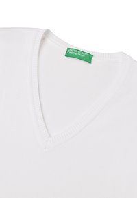 T-shirt bianca in cotone a V con scollatura a costine, con un'etichetta verde che riporta la scritta "UNITE COLORS OF BENETTON." Texture liscia, design informale.