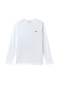 Hvid langærmet T-shirt lavet af bomuld, med et lille grønt Lacoste-logo på venstre brystområde. Glat tekstur, rund halsudskæring.