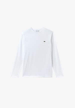 T-shirt bianco a maniche lunghe in cotone, con un piccolo logo verde Lacoste nella parte sinistra del petto. Texture liscia, scollatura rotonda.