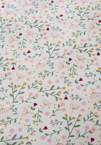 Floral cotton fabric in white features pink and red flowers, green leaves, and golden accents, creating a vibrant, repeating pattern.