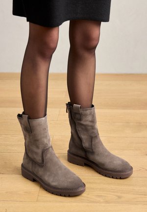 Graue Wildleder-Stiefeletten mit seitlichen Reißverschlüssen und strukturierten Sohlen. Das Design verfügt über ein enganliegendes Oberteil und eine runde Zehenpartie, auf einem breiten Absatz.