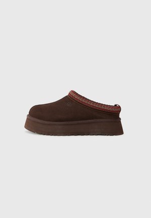 Chaussure en suède marron à enfiler avec une semelle en caoutchouc texturé, dotée d'un bord en tricot rouge et à motifs autour du col.