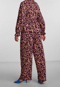 Blouse à imprimé léopard et pantalons à jambes larges dans des tons marron et rose. Tissu doux avec manches bouffantes et détails froncés à l'arrière.