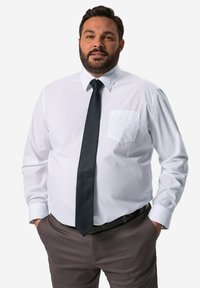 Camisa blanca de vestir con un bolsillo, mangas largas y una corbata negra. Combinada con pantalones gris, con una textura suave y un corte ajustado.