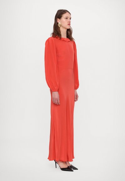 Ilga, aptempta suknelė iš ryškiai raudonos medžiagos su raukšlėtu kaklu ir pūstomis rankovėmis. Derinama su smailiais juodais aukštakulniais.