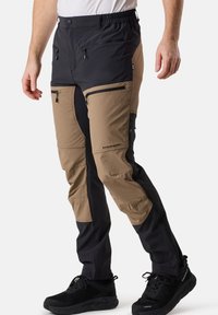 Utomhusbyxor i tvåfärgad design: svart överdel och tan underdel. Har fickor med dragkedja och elastiskt midjeband för komfort.