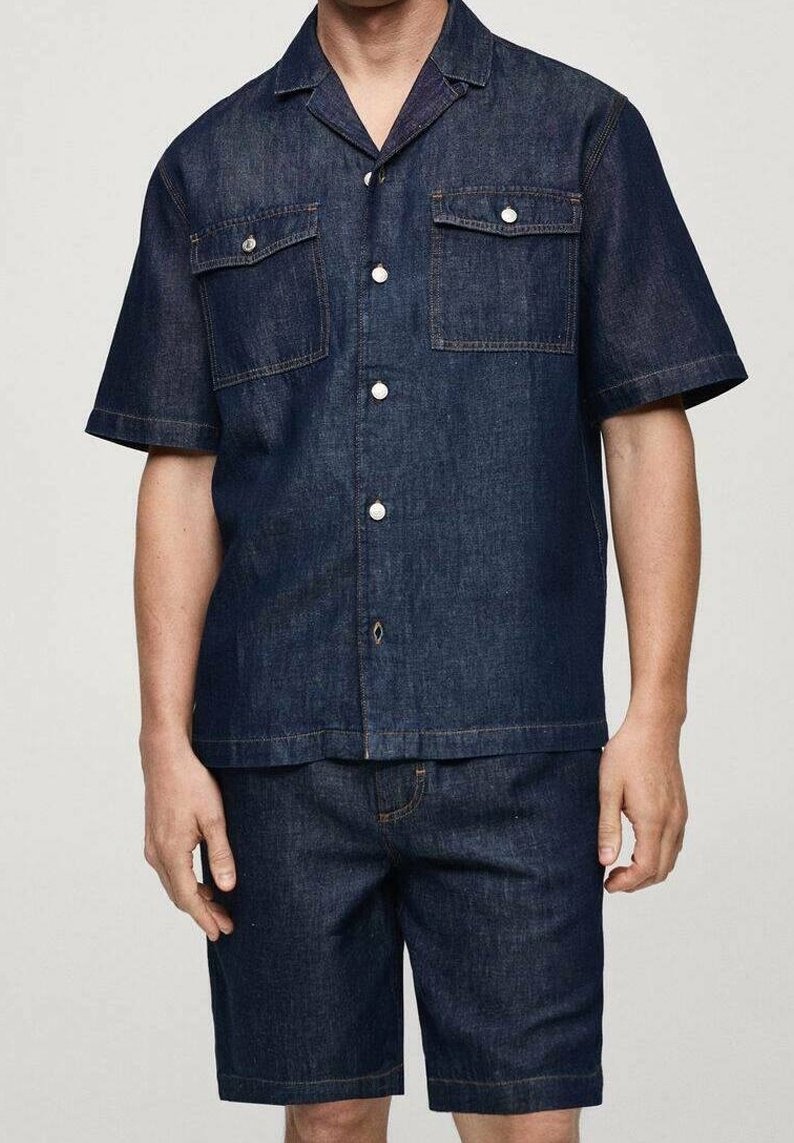 Zestaw z ciemnego denimu: koszula i szorty. Krótkie rękawy, zapięcie na guziki z przodu, dwie kieszenie na piersi. Charakteryzuje się kontrastowymi szwami i luźnym krojem.